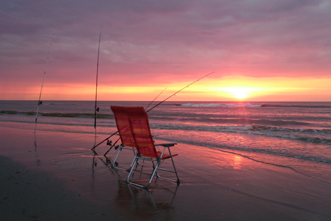 Vissen op Noordzeestrand Terschelling bij zonsondergang